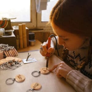 DIY wooden keychain being engraved with a wood burning tool; blank beech wood for laser engraving.
