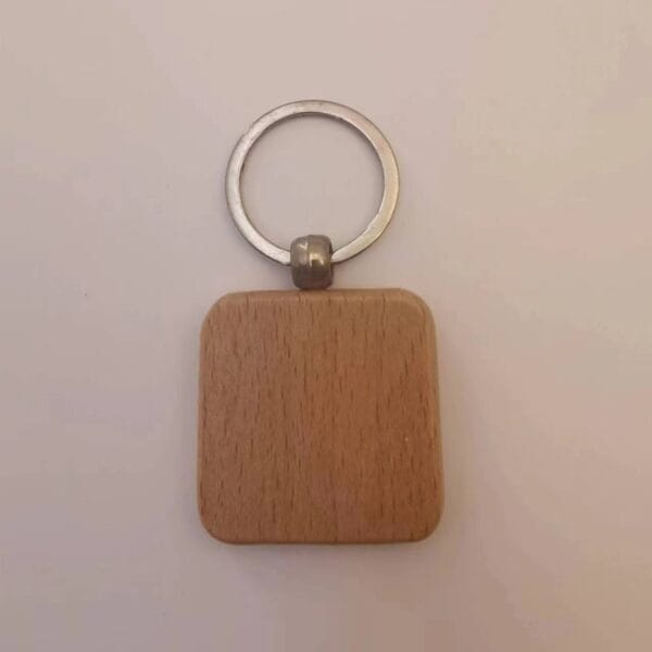 A square wooden keychain with rounded edges and a silver metal ring, placed on a plain light background.