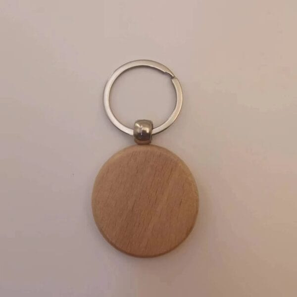A plain, round wooden keychain with a silver metal ring, placed on a white surface.