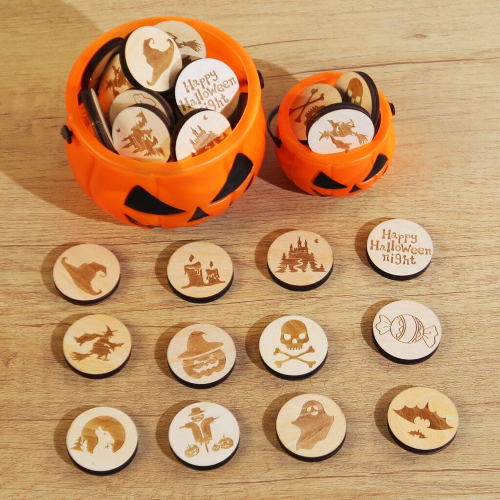 Wooden discs with Halloween-themed engravings are spread out on a wooden surface, with two orange pumpkin containers holding more discs in the background.