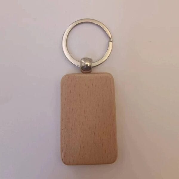 A rectangular wooden keychain with rounded edges attached to a metal keyring, placed on a plain, light-colored surface.