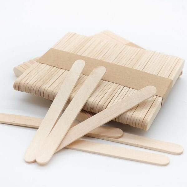 A bundle of Wood Sticks For Crafts is secured with a paper band, while several loose sticks are scattered in front on a white surface.