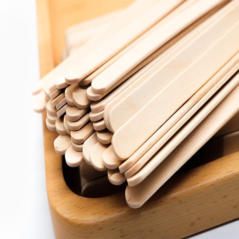 A stack of Wood Sticks For Crafts is neatly arranged on a wooden tray against a clean white background.