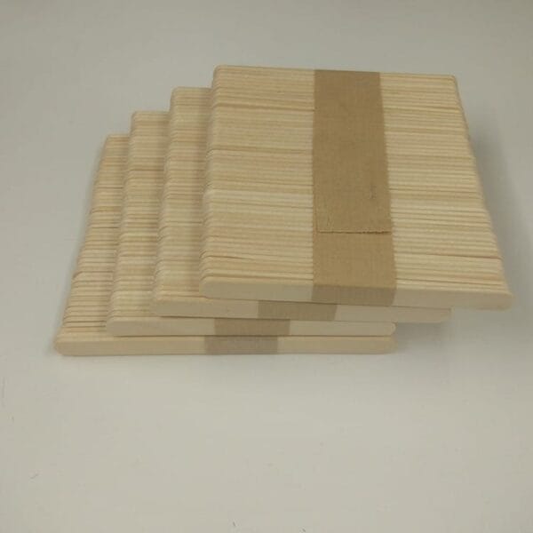 Four stacks of Wood Sticks For Crafts are bundled together with brown paper bands and neatly arranged on a plain white surface.