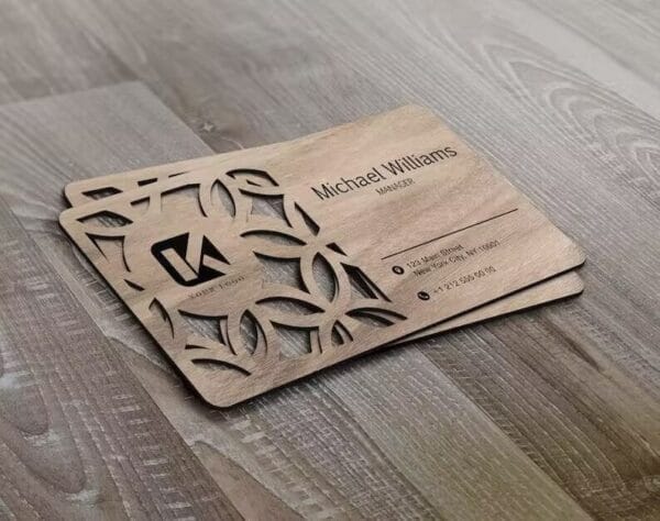 A pair of Custom Wooden Business Cards with laser-cut geometric patterns and engraved contact info for manager Michael Williams, elegantly displayed on a wooden surface.