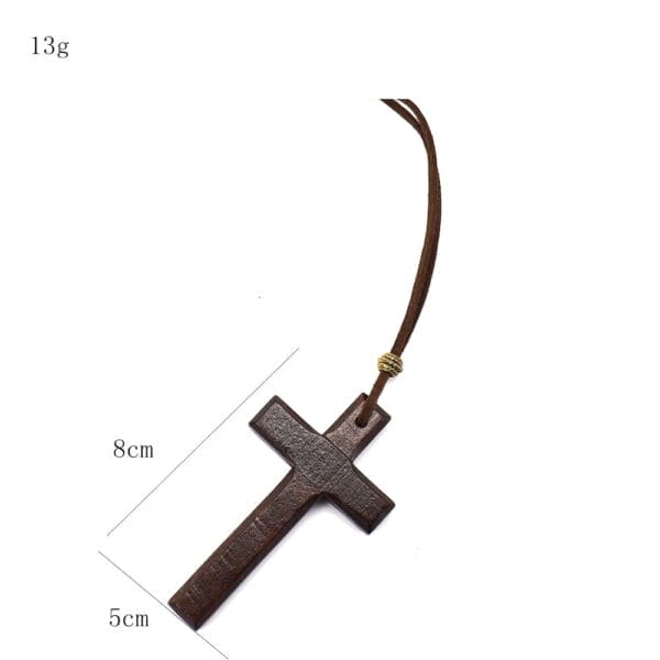 A vintage wooden cross necklace on a brown cord, measuring 8 cm by 5 cm and weighing 13 grams. This unisex necklace makes a perfect long sweater chain accessory.