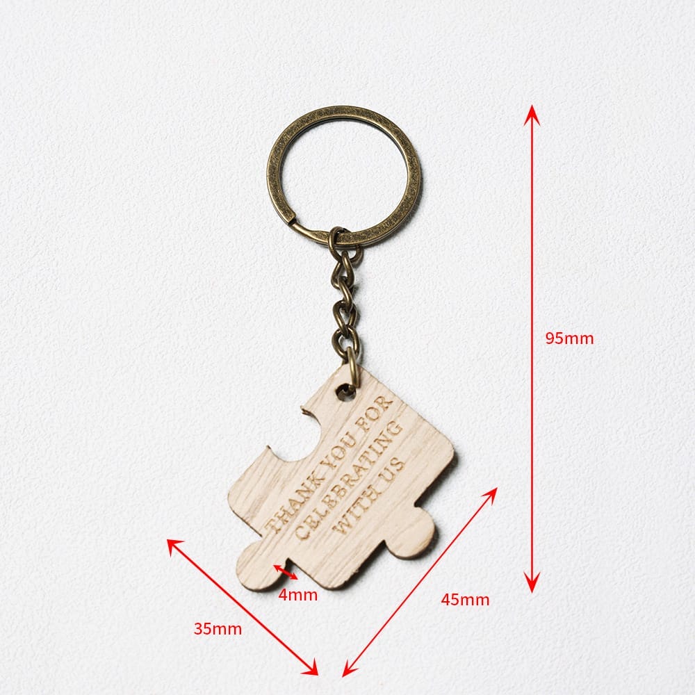 A metal keyring with a wooden puzzle piece charm engraved with “THANK YOU FOR CELEBRATING WITH US.” Red measurement lines show the keychain’s dimensions: 95mm, 45mm, and 35mm.