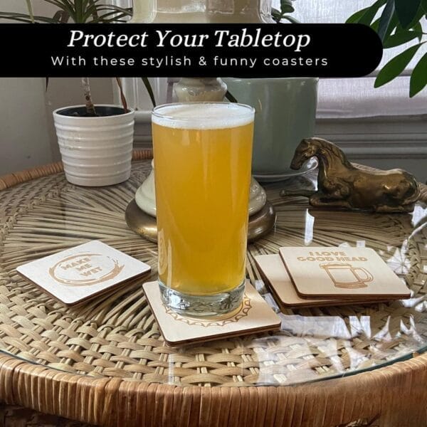 A glass of orange beverage sits on a wooden coaster on a wicker table, surrounded by Wooden Beer Coasters with engraved designs, potted plants, a lamp, and a decorative horse statue.