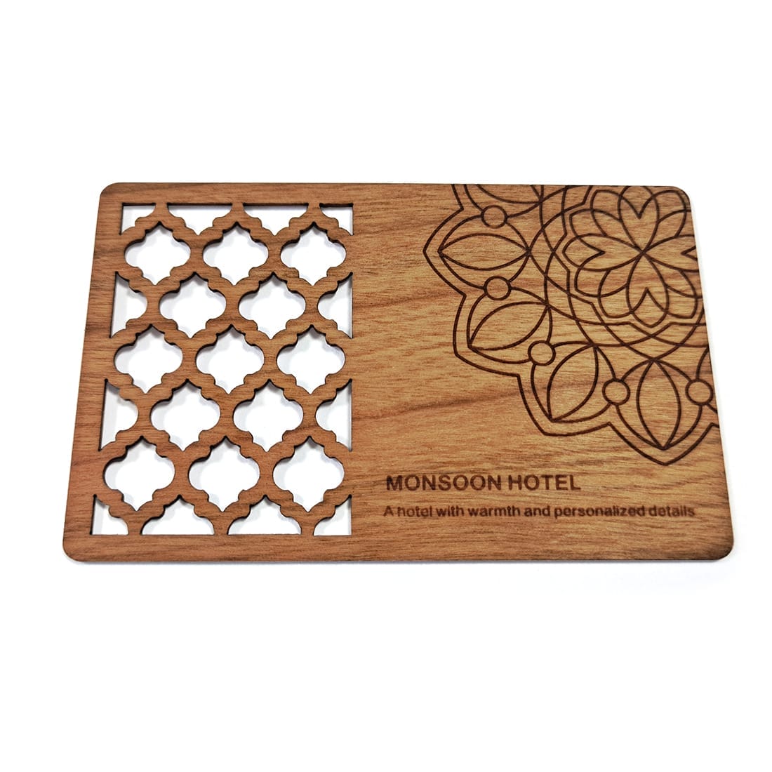 A rectangular Wooden Business Card featuring a decorative cutout pattern and mandala design, labeled "Monsoon Hotel" with the tagline “A hotel with warmth and personalized details.”.