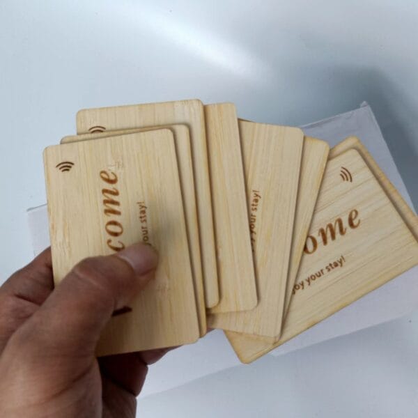 A hand holding several wooden key cards with the word “Welcome” and a wireless symbol engraved on them.