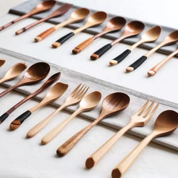A variety of Japanese Style Wooden Spoons and forks with different shades and handle designs are neatly arranged in rows on a white surface.