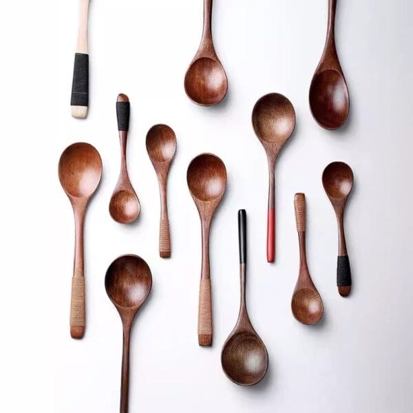 A collection of eleven handcrafted wooden spoons with varying handle designs, arranged on a white background.