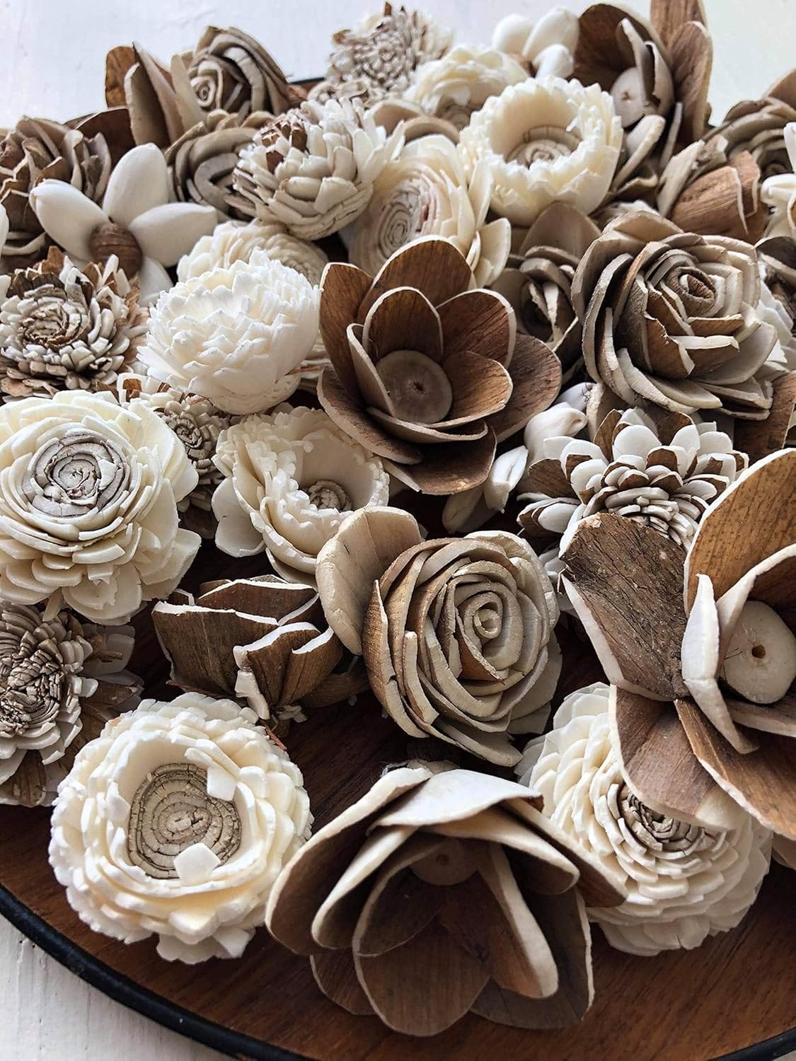 A close-up of intricately crafted Sola Wood Flowers in shades of cream and brown arranged on a wooden surface, showcasing the elegance of wooden flower bouquets.