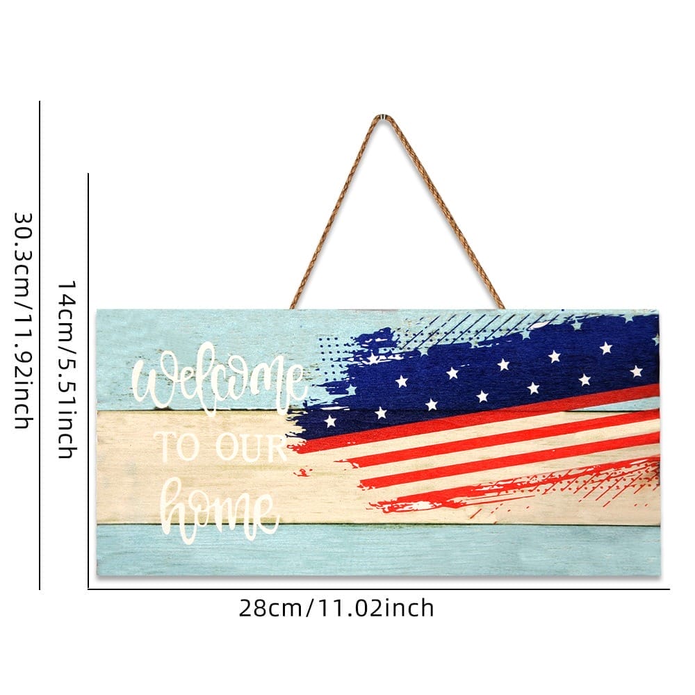 Rectangular wooden sign with "Welcome to our home" text, a wooden American flag design, and hanging rope; sign measures 28 cm by 14 cm.