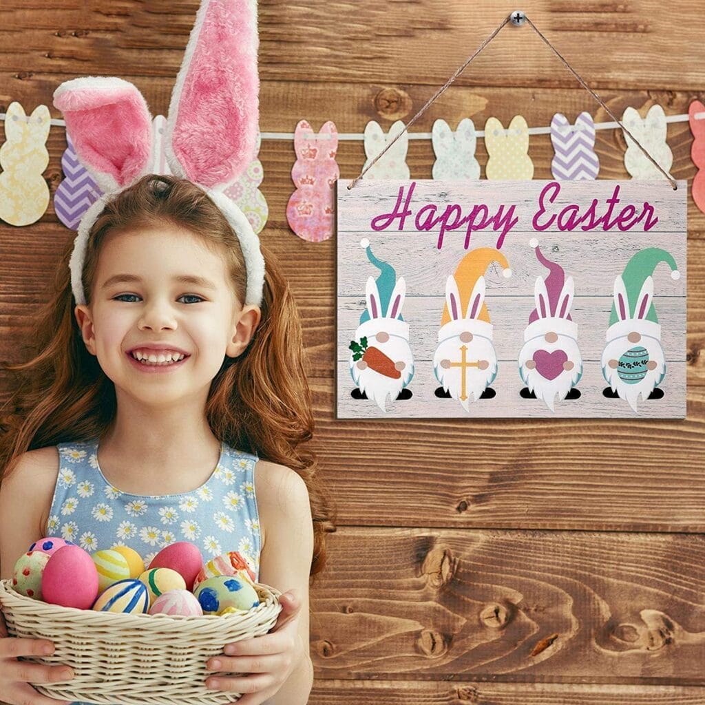 A girl wearing bunny ears holds a basket of Easter eggs and stands next to a "Happy Easter" sign with gnome illustrations, against a wooden background decorated with bunny cutouts.