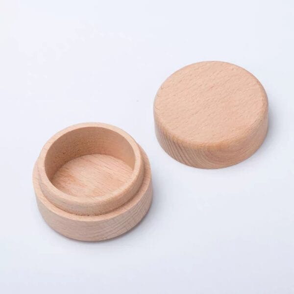 A round wooden container with a matching removable lid, both resting on a white surface.