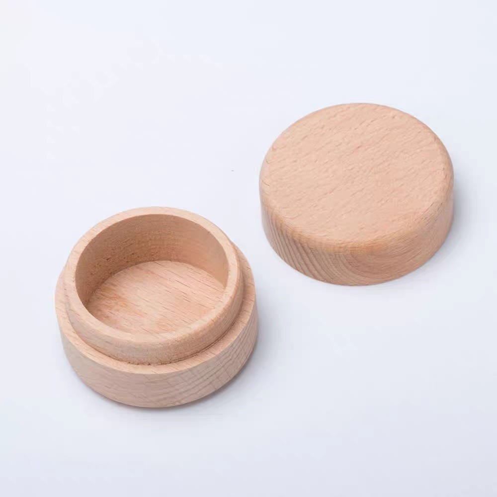 A round wooden container with a matching removable lid, both resting on a white surface.