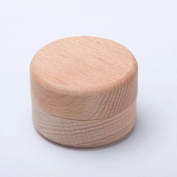 A small, round, light wooden container with a fitted lid, placed on a plain white background.