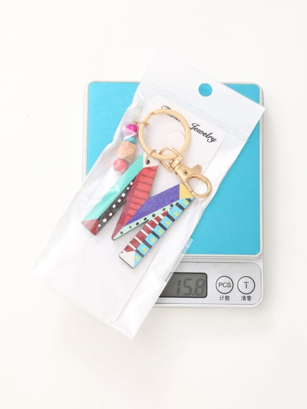 Colorful letter M wood bead keychain from Wholesale Wood Bead Keychain Manufacturer, on a scale.