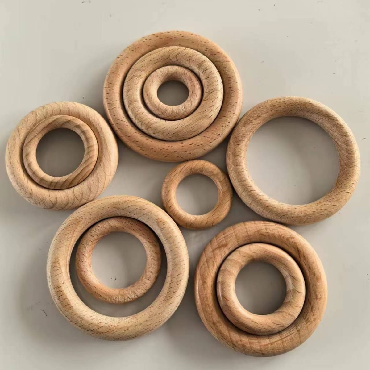 Seven groups of round, nested beech wood rings of varying sizes arranged on a light surface—perfect as wooden ring craft supplies for DIY projects.