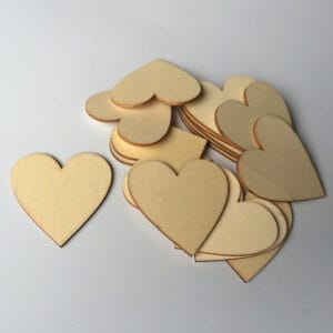Wooden heart craft decorations: A pile of unfinished light-colored wooden hearts, perfect for DIY projects.