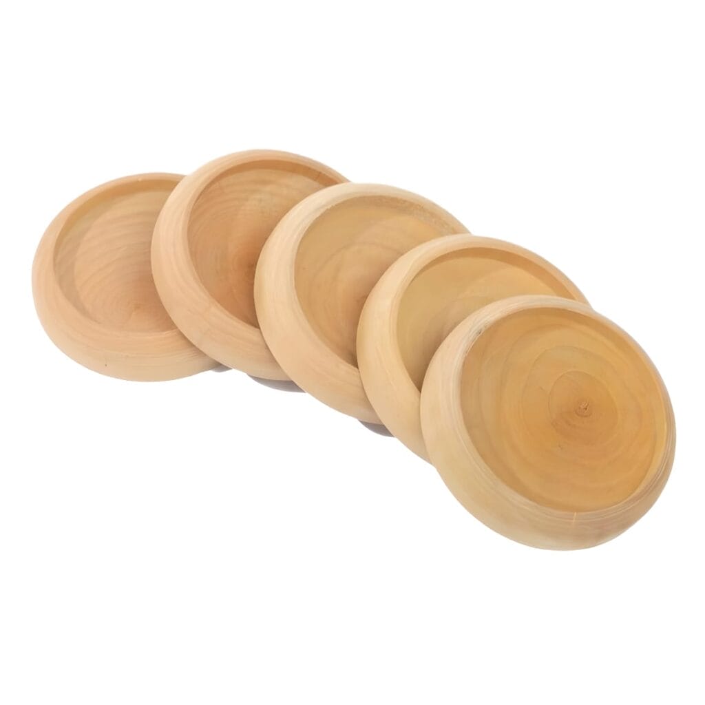 Four round, light-colored wooden coasters—reminiscent of a circle wood needle holder—are arranged in a slightly overlapping, diagonal row on a white background.