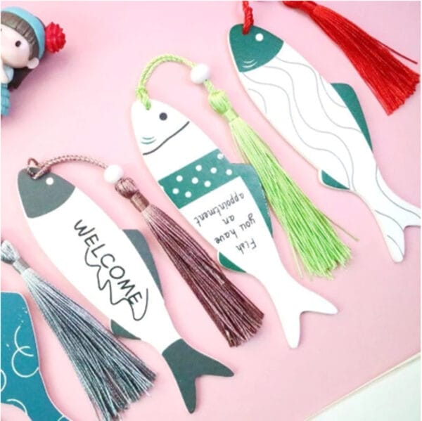 Four fish-shaped eco-friendly bookmarks with colorful tassels are arranged side by side. Some have text, including "WELCOME" and "Fish you well on appointment," making these wooden bookmarks both charming and unique.