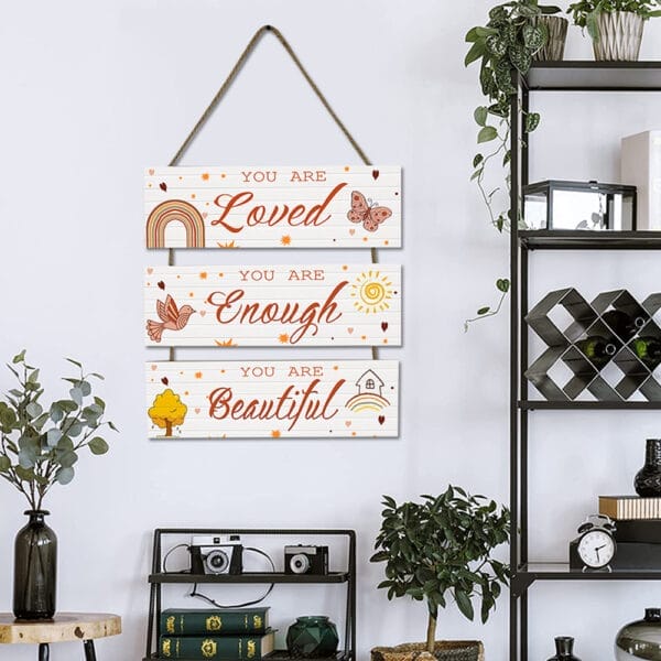A wall hanging with three wooden plaques reads: "You are Loved," "You are Enough," and "You are Beautiful," decorated with simple nature-themed illustrations.