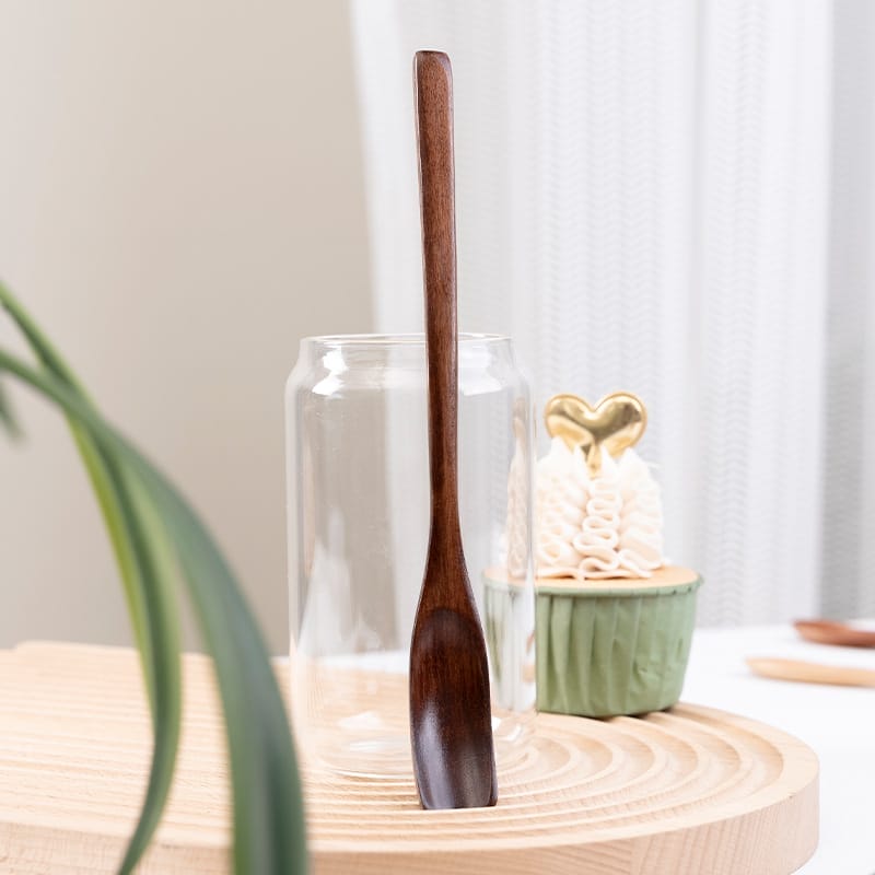 Wooden coffee bean spoon in glass, next to cupcake. Wholesale honey spoon supplier.