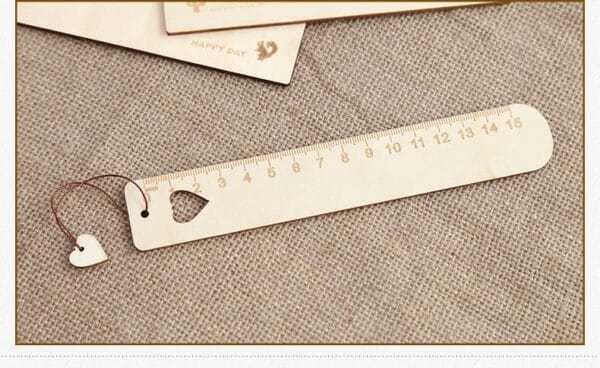 A wooden engraved ruler with centimeter markings from 1 to 15, featuring a heart-shaped cutout and a small heart charm attached with a string—perfect for custom gifts or laser cut wood bookmarks.