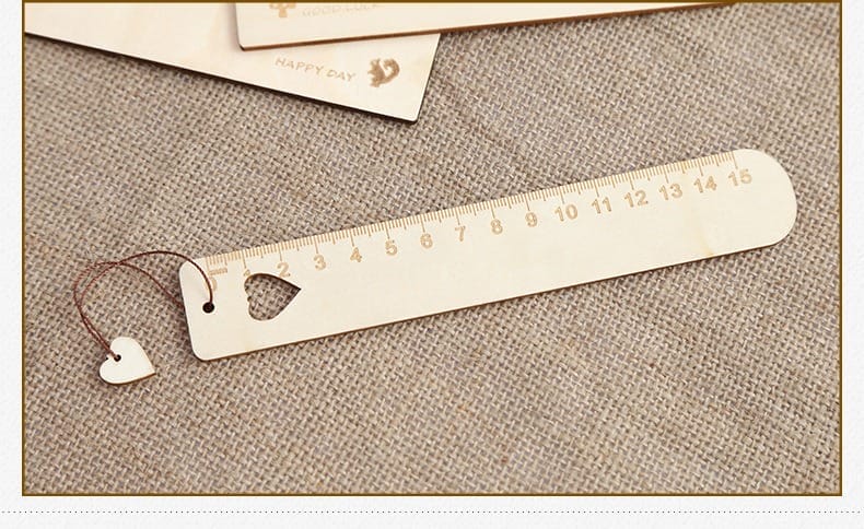 A wooden engraved ruler with centimeter markings from 1 to 15, featuring a heart-shaped cutout and a small heart charm attached with a string—perfect for custom gifts or laser cut wood bookmarks.