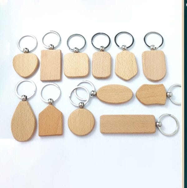 Twelve laser cut wood keychains in various shapes and sizes are arranged on a white background.