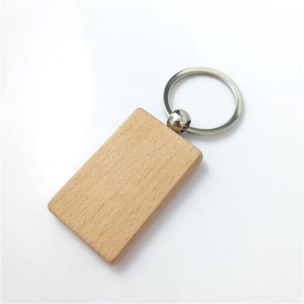 A rectangular laser cut wood keychain with a metal key ring, placed on a white surface. Perfect for wholesale orders and crafted from quality beech wood.