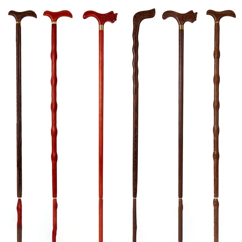 Six wooden walking canes, each crafted from long stick wood with curved handles, are displayed upright on a white background. The canes vary in color, texture, and handle shape.