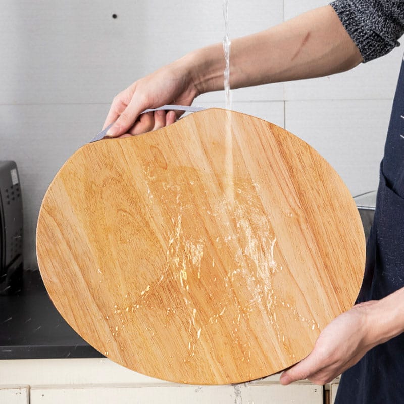 Person washing a large, round, eco-friendly round wooden cutting boards. Wholesale supplier of wooden boards.