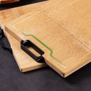Two solid wood chopping boards, one with a black handle. Eco-friendly kitchenware.