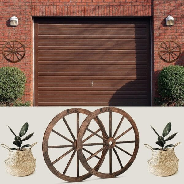 A brown garage door with two Rustic Wheel accents mounted on the brick wall, displayed above standalone decorative wagon wheels and two potted plants in woven baskets.