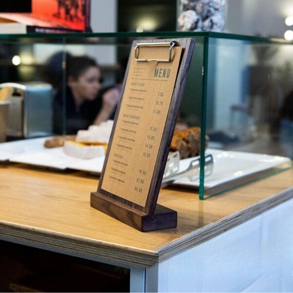 Wooden A4 menu holder displaying prices on a cafe counter.