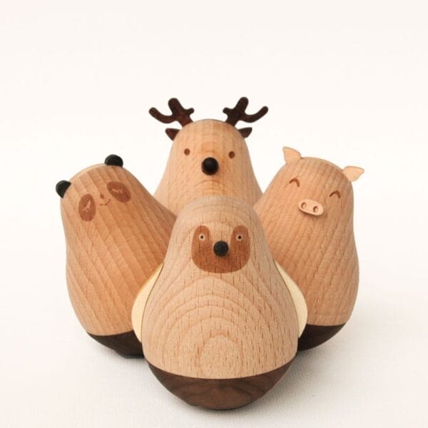 Four wooden animal figurines—a bear, a deer reminiscent of Nordic reindeer decorations, a pig, and a penguin—are arranged together on a plain white background, showcasing beautiful wooden crafts.