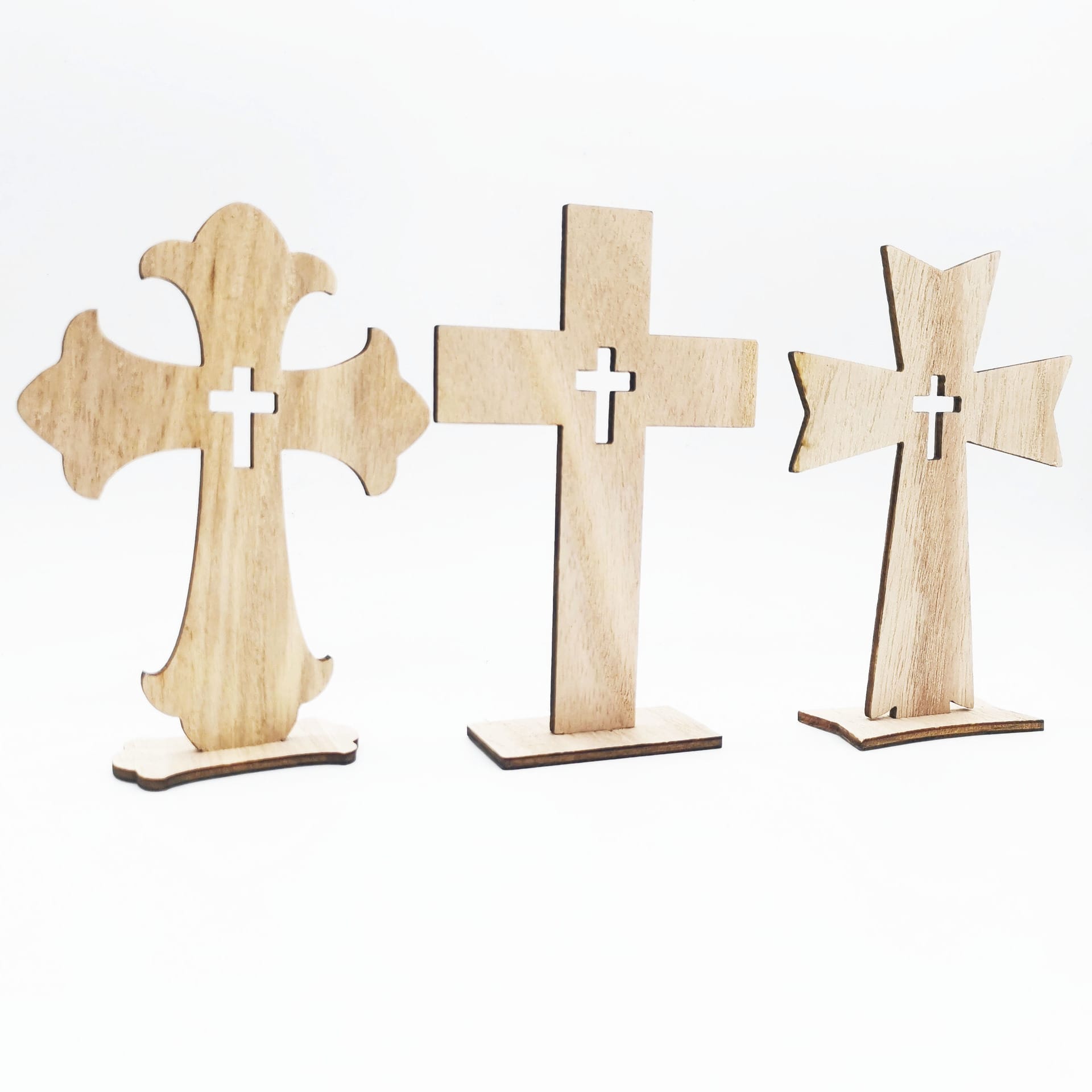 Three wooden crosses with different shapes and cutout centers are standing upright on a white background, perfect as a wood cross craft or part of a handmade decorative set from a wholesale manufacturer.