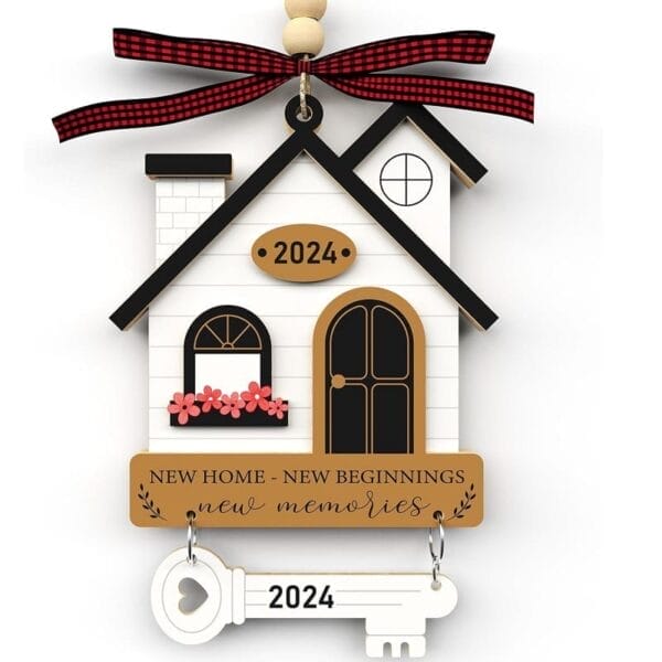 A decorative wood gift house ornament with "2024" and "New Home - New Beginnings - New Memories" text, featuring a white key labeled "2024" and a red plaid ribbon on top.