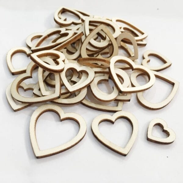 A pile of eco-friendly wooden heart-shaped cutouts in various sizes is scattered on a white surface, perfect for crafts and décor.