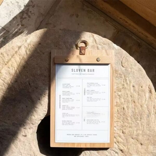 Rustic wood menu holder with Sloven Bar menu, showcasing craft brews and cocktails.