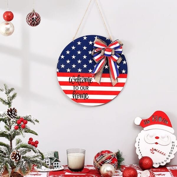 A round American flag-themed wood plaque with a bow and "Welcome to our home" hangs on a wall, surrounded by Christmas decorations and a Santa countdown calendar.
