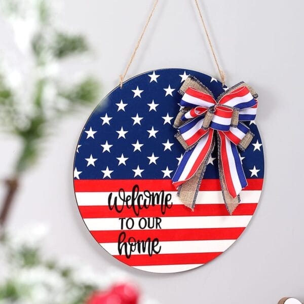 A round custom wooden door hanger with an American flag design, ribbon, and “Welcome to our home” text, perfect for celebrating Independence Day USA, displayed against a light-colored wall.