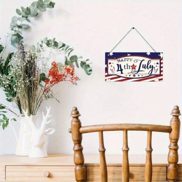 A wooden chair sits in front of a white wall with a "Happy 4th of July" Custom Wooden Door Sign and a vase of dried flowers on a white table, creating charming home decor.