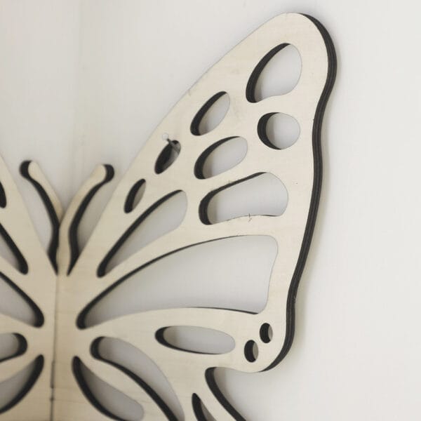 A close-up of a decorative wooden butterfly wing mounted on a white wall.