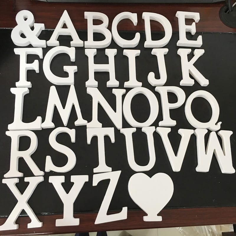 White uppercase woodcut letters of the English alphabet and a heart shape are arranged in rows on a dark surface.