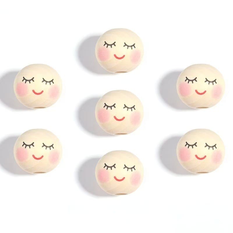 Six round balls with painted closed eyes, smiling mouths, and rosy cheeks are arranged in a grid pattern on a white background.