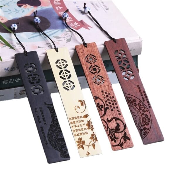 Four intricately carved wooden bookmarks, featuring Chinese style window pattern designs and decorative text, are displayed on top of stacked books—perfect as unique laser engraved gifts.